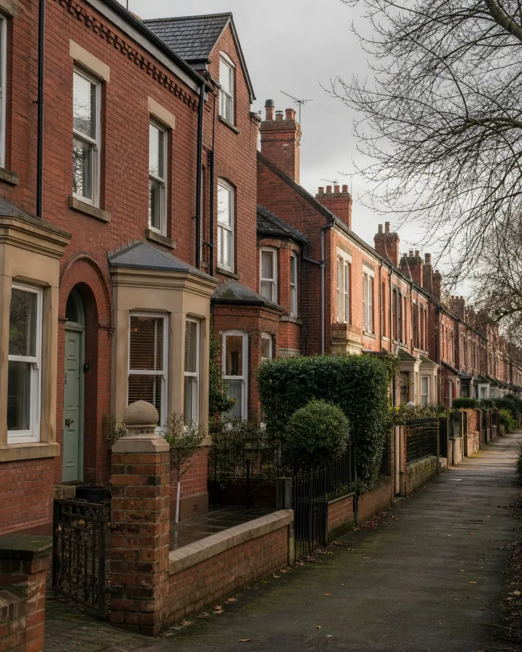 Red-brick Victorian terraces and front hedges along a Rusholme street